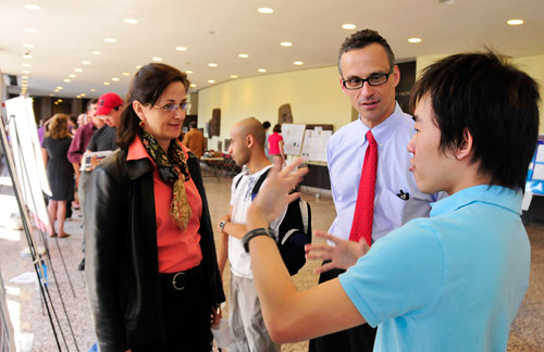 Jan Naegele, chair and professor of biology, professor of neuroscience and behavior, and Wesleyan President Michael Roth listen to Kai Xuan Keith Tan explain his research during the Natural Science and Mathematics Poster Session April 17. Tan's project was titled "The Role of Ku70 in Regulating Cell Death during Cerebral Cortical Development."