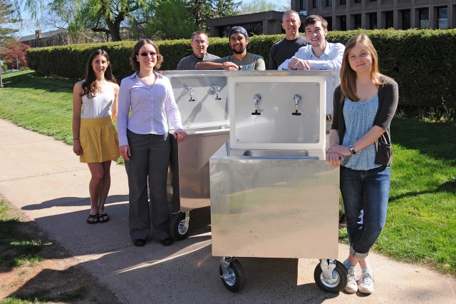 From left, Nina Gerona '15; Jen Kleindienst, sustainability coordinator; Bruce Strickland, instrument maker specialist; Tavo True-Alcalá '15; Dave Strickland, instrument maker specialist; Brent Packer '15; and Madeleine O’Brien '16 present the student-designed "Wishing Well." The project was constructed by the Machine Shop inside Wesleyan's Scientific Support Services. 