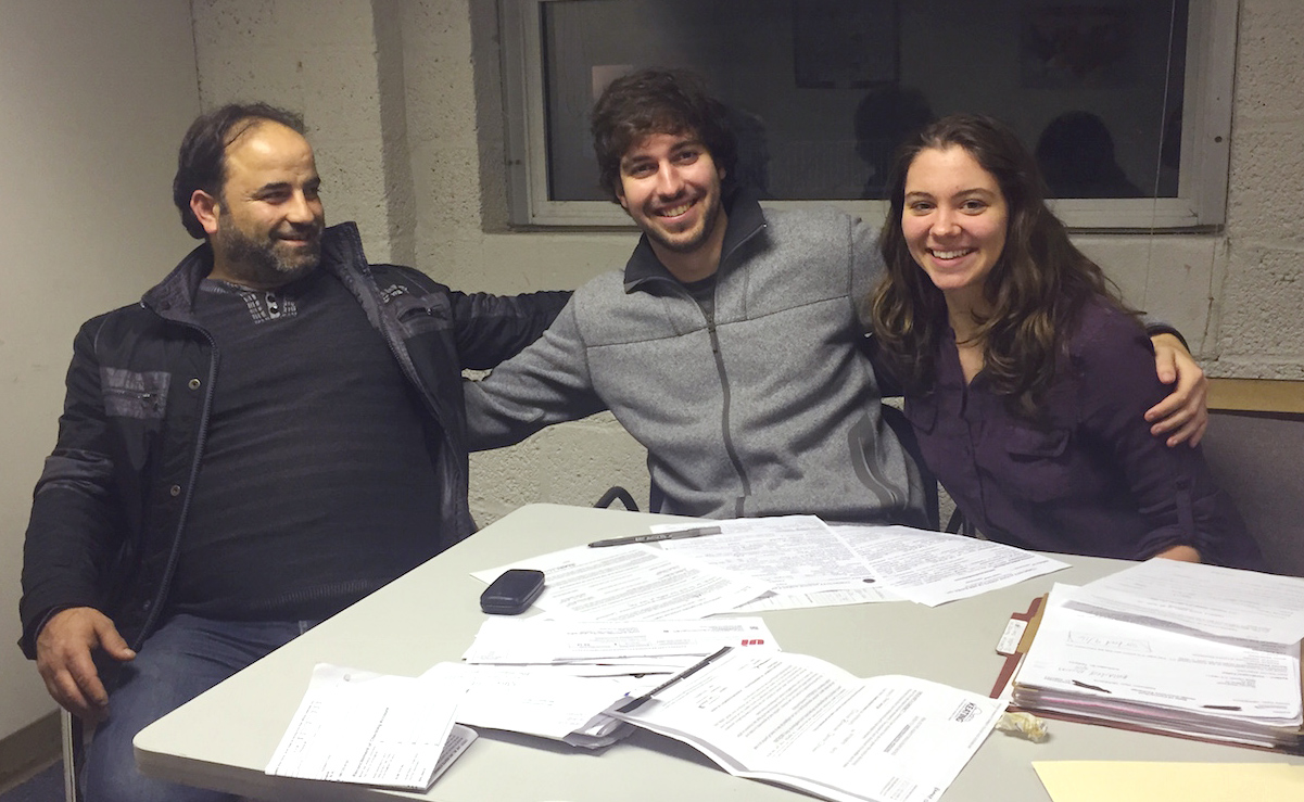 Cole Phillips ’16, center, and Sophie Zinser ’16, right, volunteer every week at Integrated Refugee and Immigrant Services (IRIS) in New Haven, helping refugees apply for housing and energy subsidy programs. Here, they are pictured with Ramez al-Darwish, a Syrian refugee from Homs.