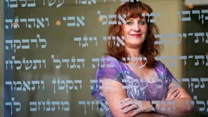 Cheri Weiss '83, a cantorial intern at Congregation Beth El in La Jolla, looks through scripture found on the glass walls of the synagogue. She has recorded a CD of High Holy Days prayers and songs that she's distributing free to shut-ins. (Photo by Nancee E. Lewis)