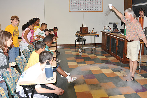 Brian Stewart, associate professor pf physics, demonstrates how liquid nitrogen looks like water but evaporates rapidly at room temperature. Fifth grade students from Snow Elementary School toured the Wesleyan sciences June 19. 
