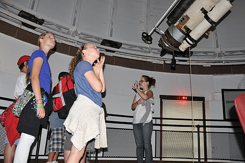 Astronomy graduate student Amy Langford, at right, teaches the students about Wesleyan's Alvan Clark 20-inch refractor telescope inside the observatory. (Photos by Olivia Bartlett)