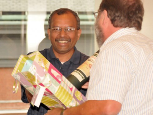 John Meerts, vice president for finance and administration, "bribes" Ravi with a gift during the farewell celebration. Ravi will begin a new career as the vice president and chief information officer at Pace University. He will be responsible for supporting computing at Pace's three New York campuses in White Plains, Westchester and Manhattan. 