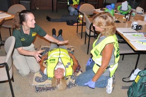 Holly Jacobs from the Manchester Community Emergency Response Team (CERT) left, teaches Joyce Topshe, associate vice president for facilities, at right, how to properly give a “head-to-toe assessment” on an accident victim. Stacy Baldwin, construction project coordinator, plays the role of an injured person. 