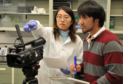 Molecular biology and biochemistry graduate student Jie Zhai explains a scene for videographer Kai-Jie Wang Dec. 15 inside the Hingorani Laboratory. Wang works for the Journal of Visualized Experiments, a peer reviewed, indexed journal devoted to the publication of biological research in a video format. He is filming a project at Wesleyan titled Application of Stopped-flow Kinetics Methods to Investigate the Mechanism of Action of a DNA Repair Protein. 