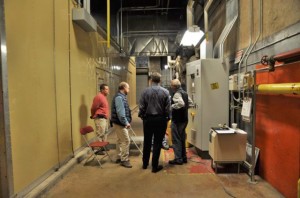 The Central Power Plant team discusses the performance of the main “island mode” generator, located behind the wall on the left.