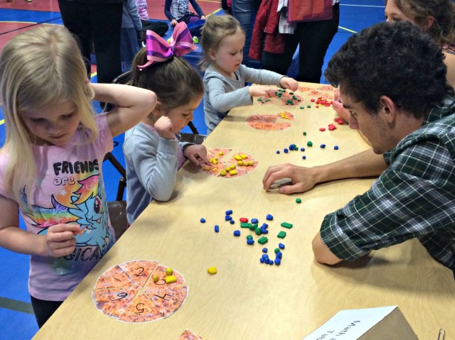 Davey Bales ’15 and Julia Vermeulen ’15 play a math game with Eliana, Carly and Sam at Family Math Night.