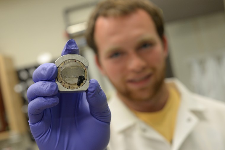 Jack Singer '15 holds a fragmented lunar sample (Apollo 12039,3), a crucial sample for studying his mineral of interest — apatite — on the moon.