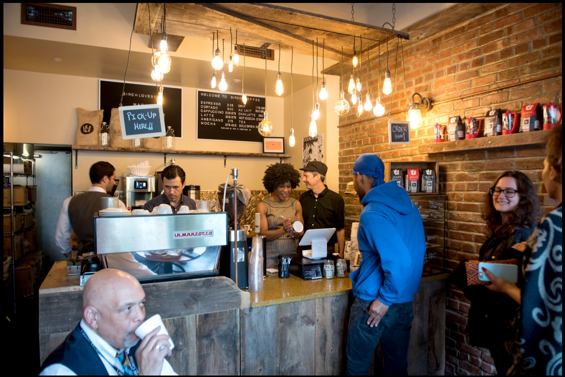 Majora Carter ’88, center, marks a coffee cup, as she takes an order at the Birch coffee shop she and her husband recently opened in the South Bronx. Photo credit: Edwin J. Torres for The New York Times See the photo series> 