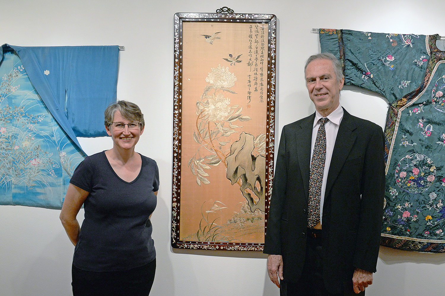 Clare Rogan, curator of the Davison Art Center, and Patrick Dowdey, curator of the Freeman Center for East Asian Studies stand near a silk embroidery titled “Peony (pre 1925)” from Southeast China. The artwork is framed in hardwood with a mother of pearl inlay. 