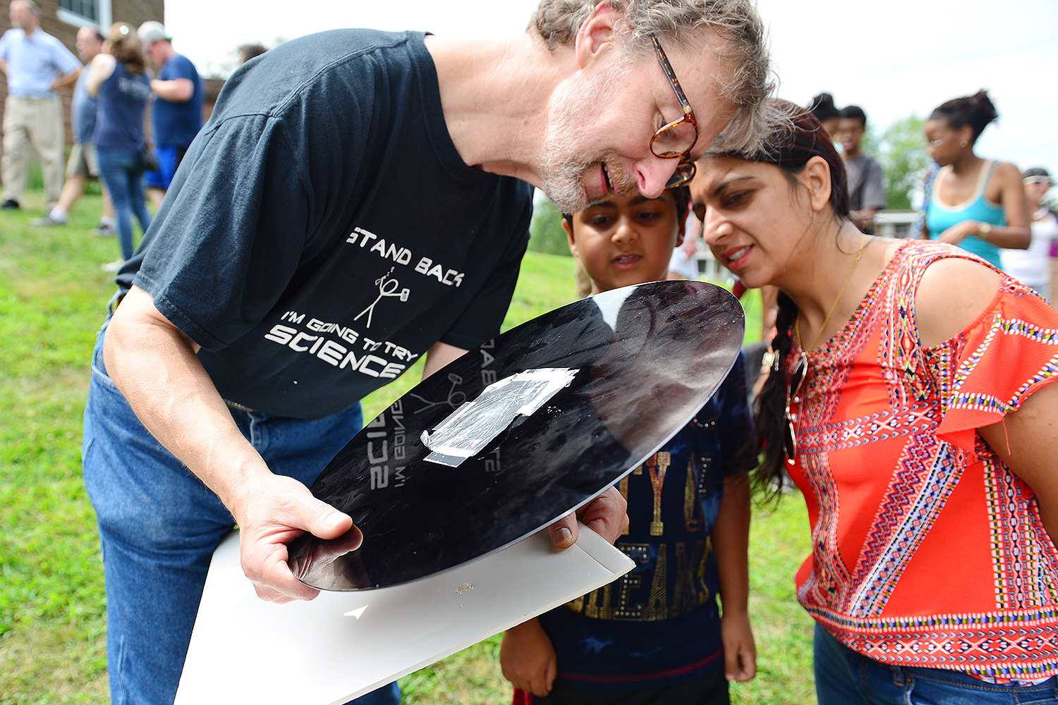 Vacek Miglus, lab technician for the Physics Department, watches the eclipse with a homemade viewing tool. 