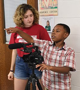 Sarah Lucente '21 works with MacDonough students Isaiah and Violet on how to operate the videocamera.