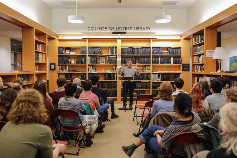 the assembled students listen intently as Greenhouse lectures at the podium.