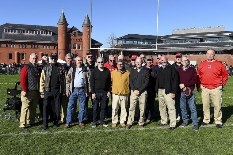 1960s Alumni Athletes and Athletic Director stand on the field