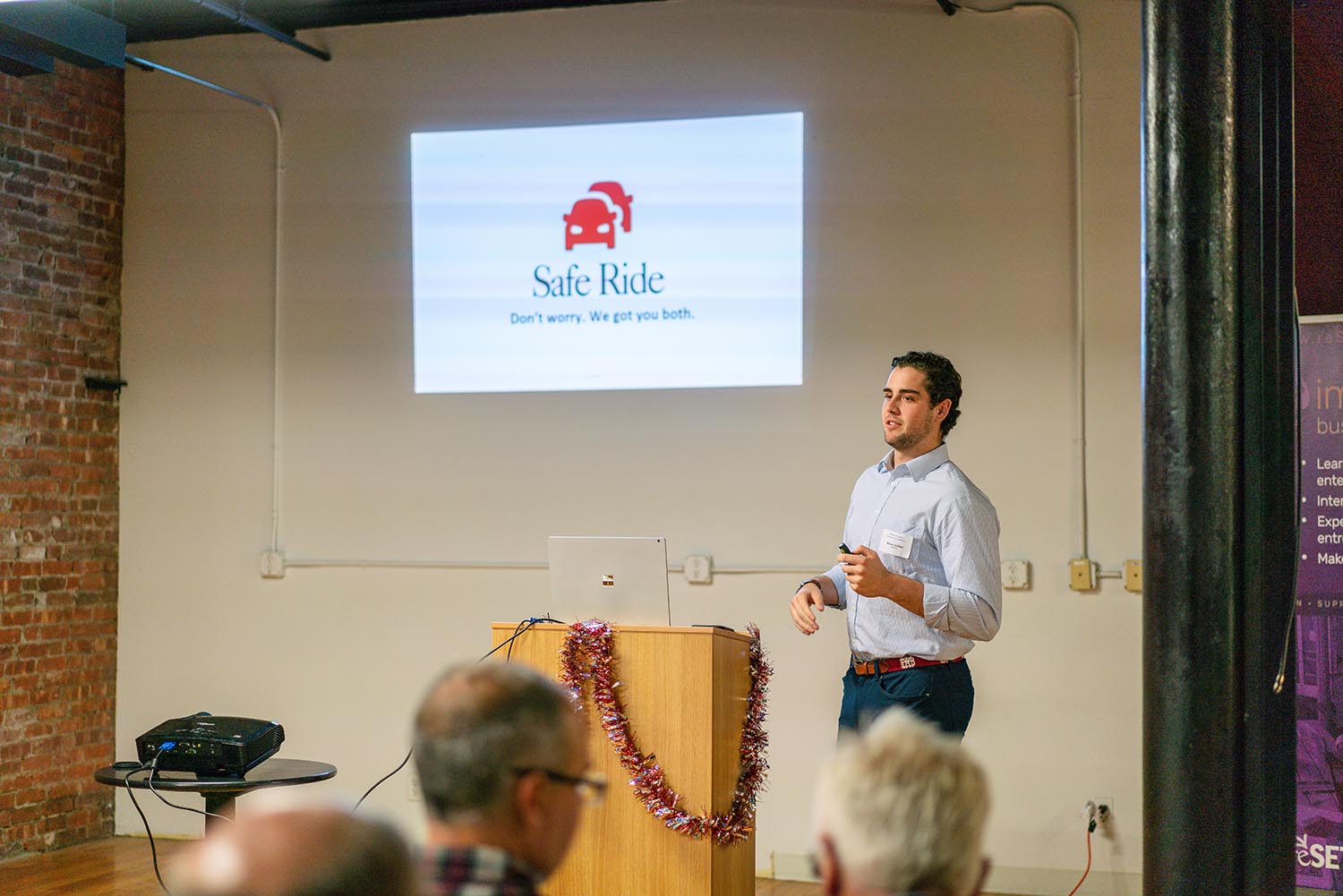 Nolan stands in front of the screen with his logo for Safe Ride